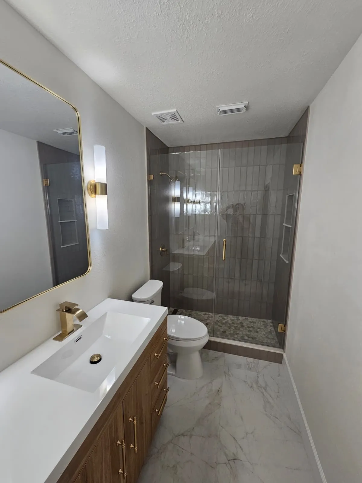 Bathroom remodel with a walnut double vanity and brushed gold fittings in Alden Bridge, The Woodlands, TX