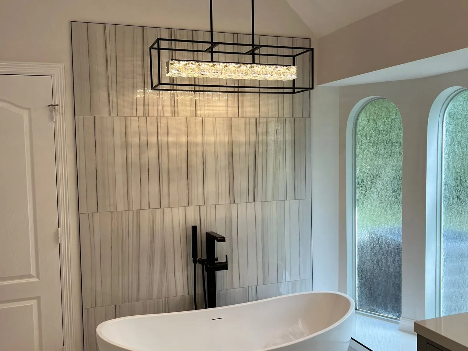 Freestanding tub beneath arched windows in a primary bathroom remodel in The Woodlands, TX