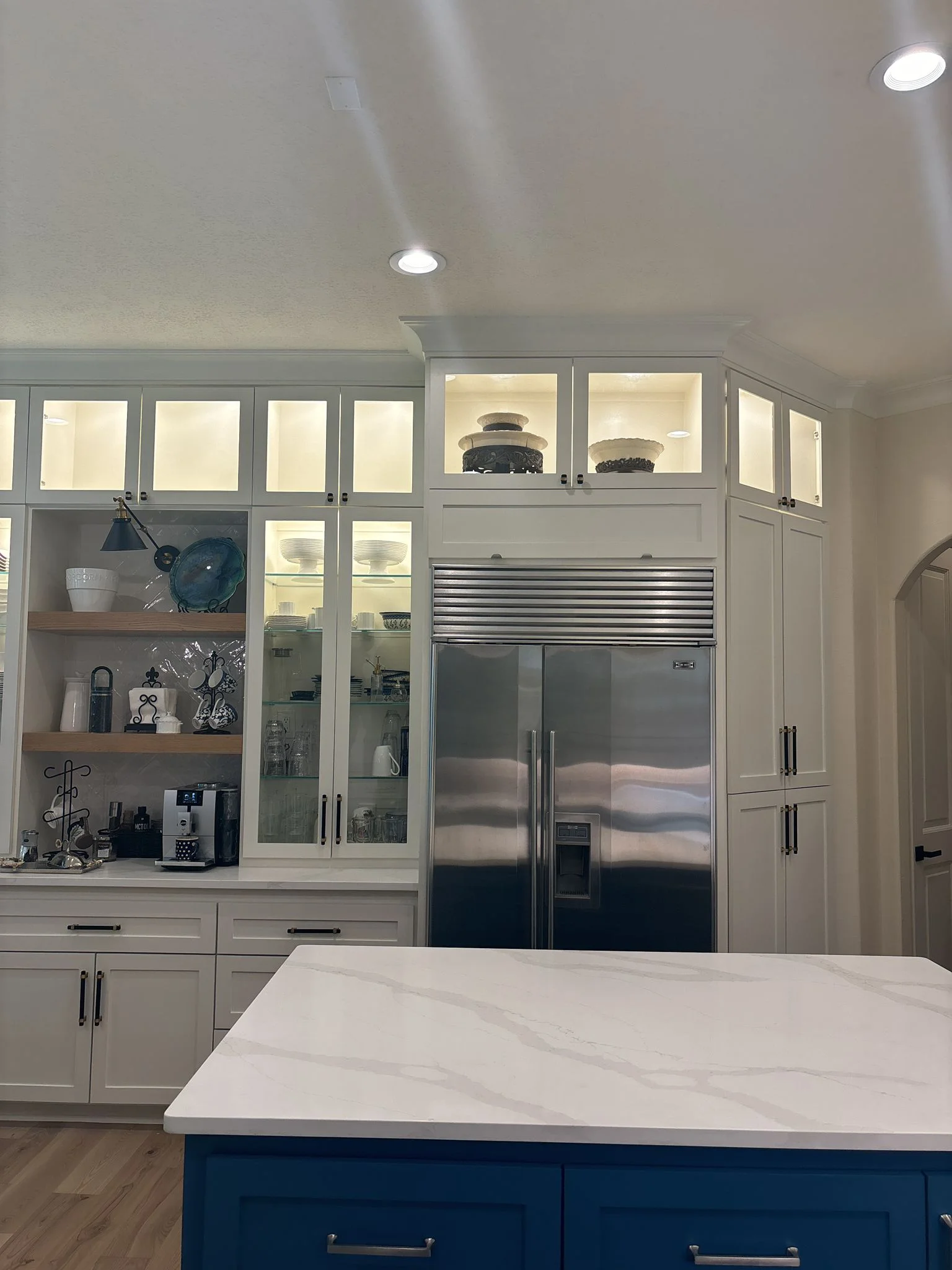 Custom glass-front cabinetry with integrated lighting and a built-in pantry surround in The Woodlands, TX