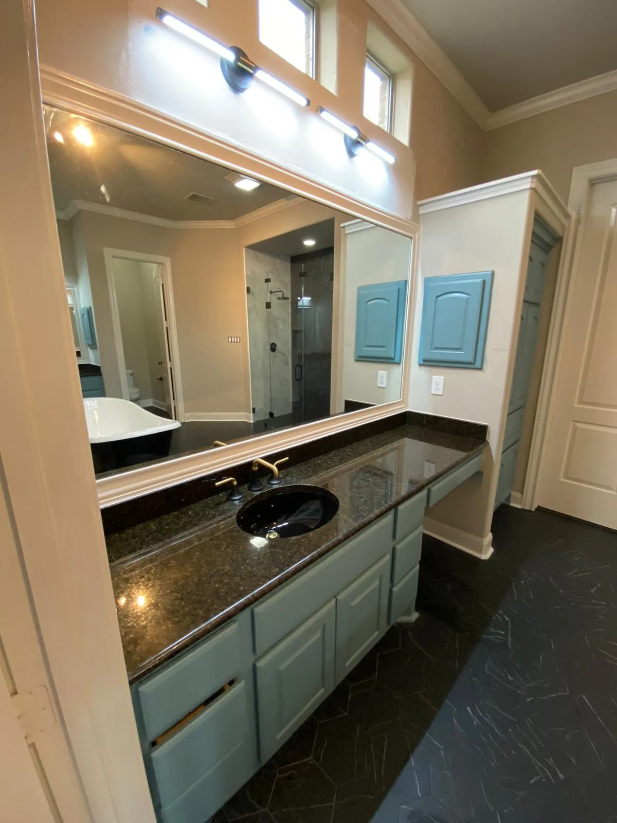 Bathroom remodel with a clawfoot tub, sage cabinetry, and gold penny-round shower tile in The Woodlands, TX