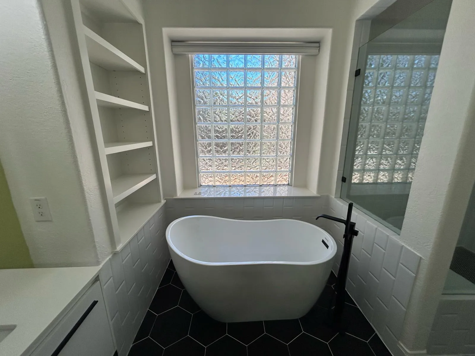 Bathroom remodel with a freestanding tub, black hexagon floor tile, and a floating vanity in The Woodlands, TX