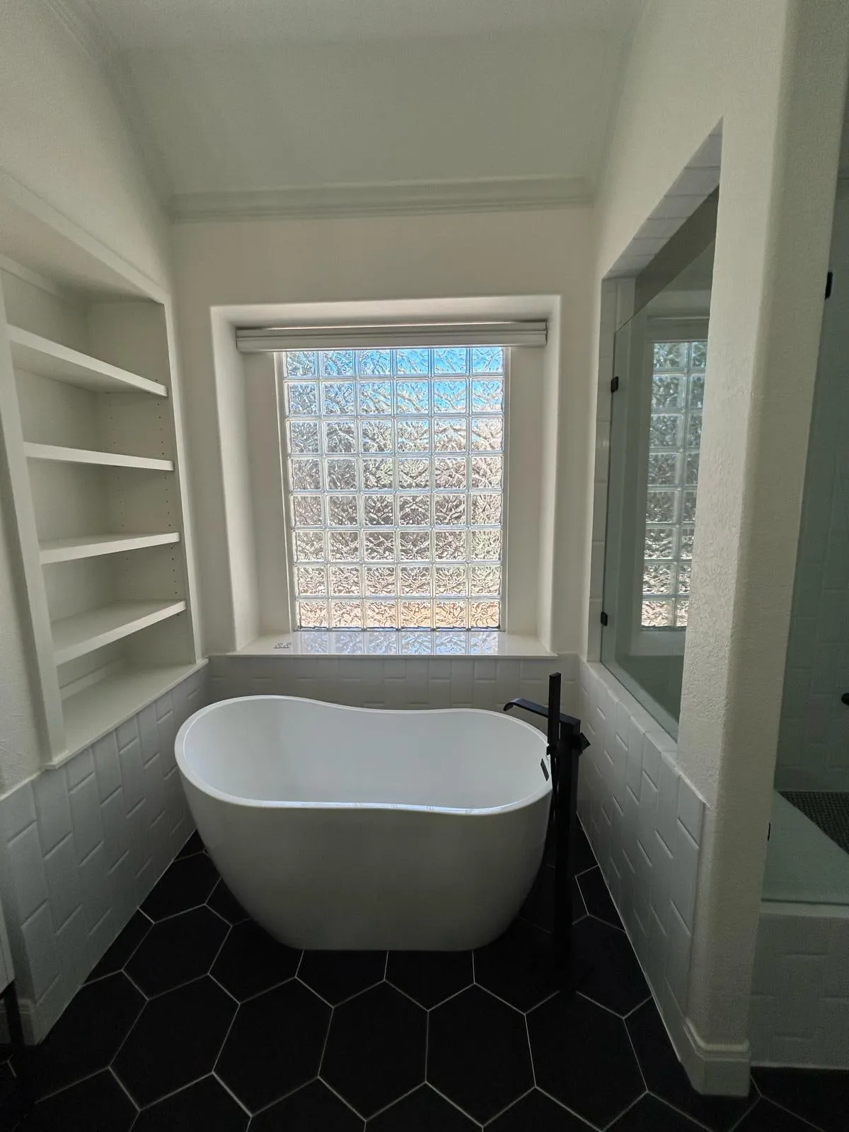 Bathroom remodel with a freestanding tub, black hexagon floor tile, and a floating vanity in The Woodlands, TX