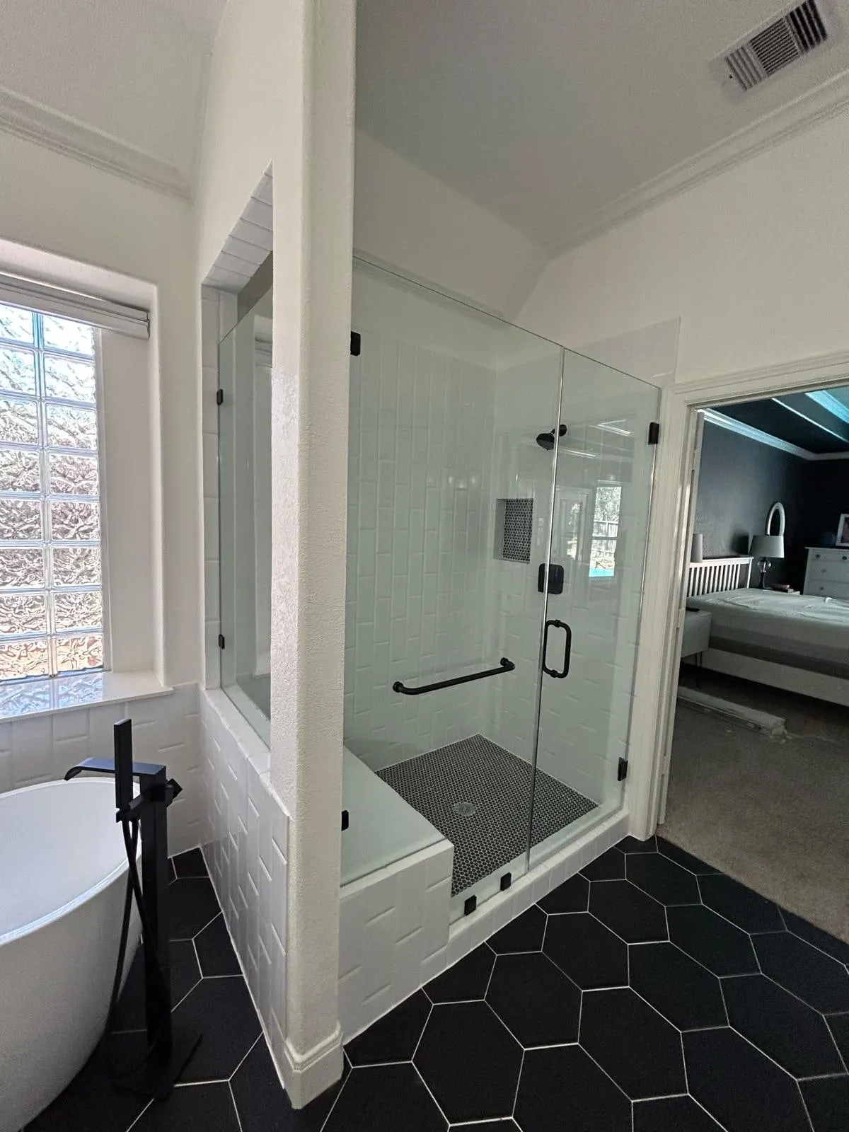 Bathroom remodel with a freestanding tub, black hexagon floor tile, and a floating vanity in The Woodlands, TX