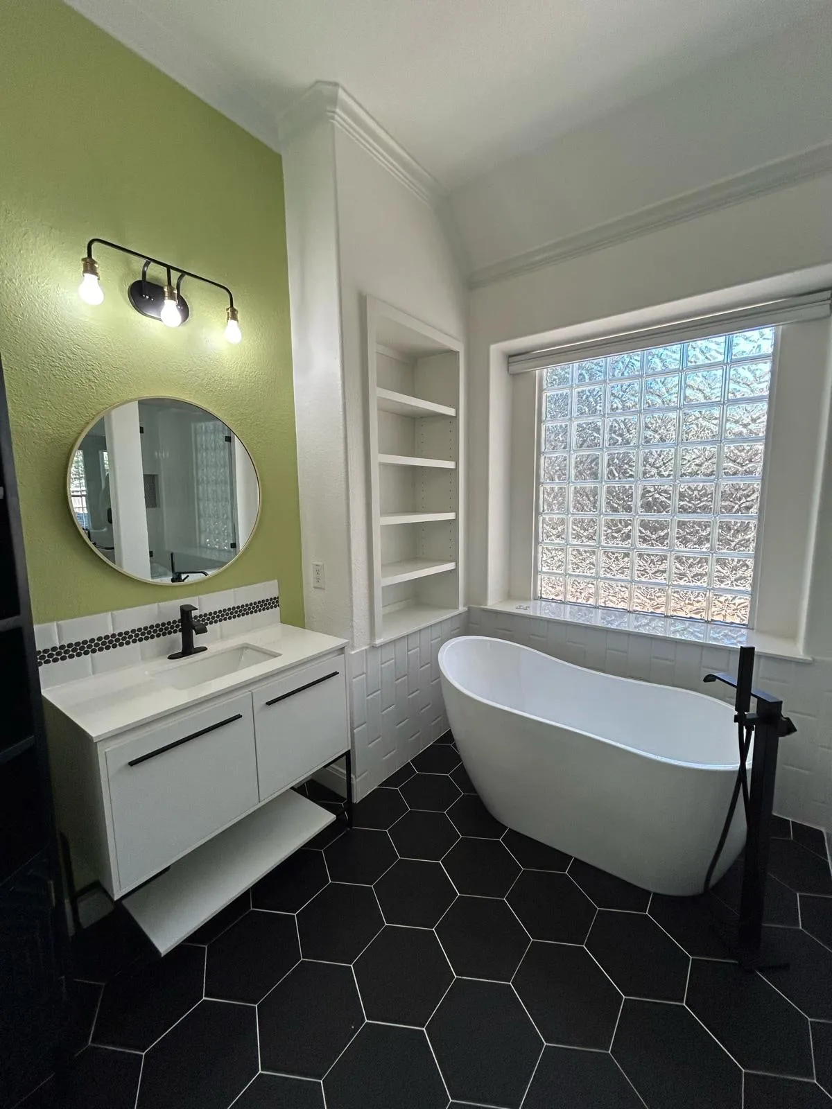 Bathroom remodel with a freestanding tub, black hexagon floor tile, and a floating vanity in The Woodlands, TX