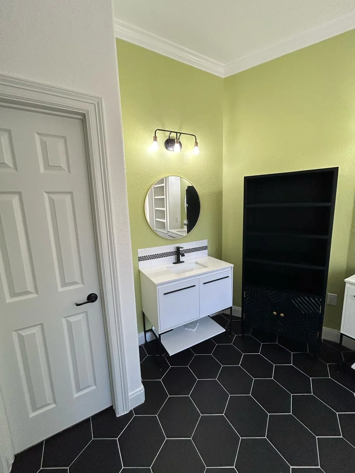 Bathroom remodel with a freestanding tub, black hexagon floor tile, and a floating vanity in The Woodlands, TX