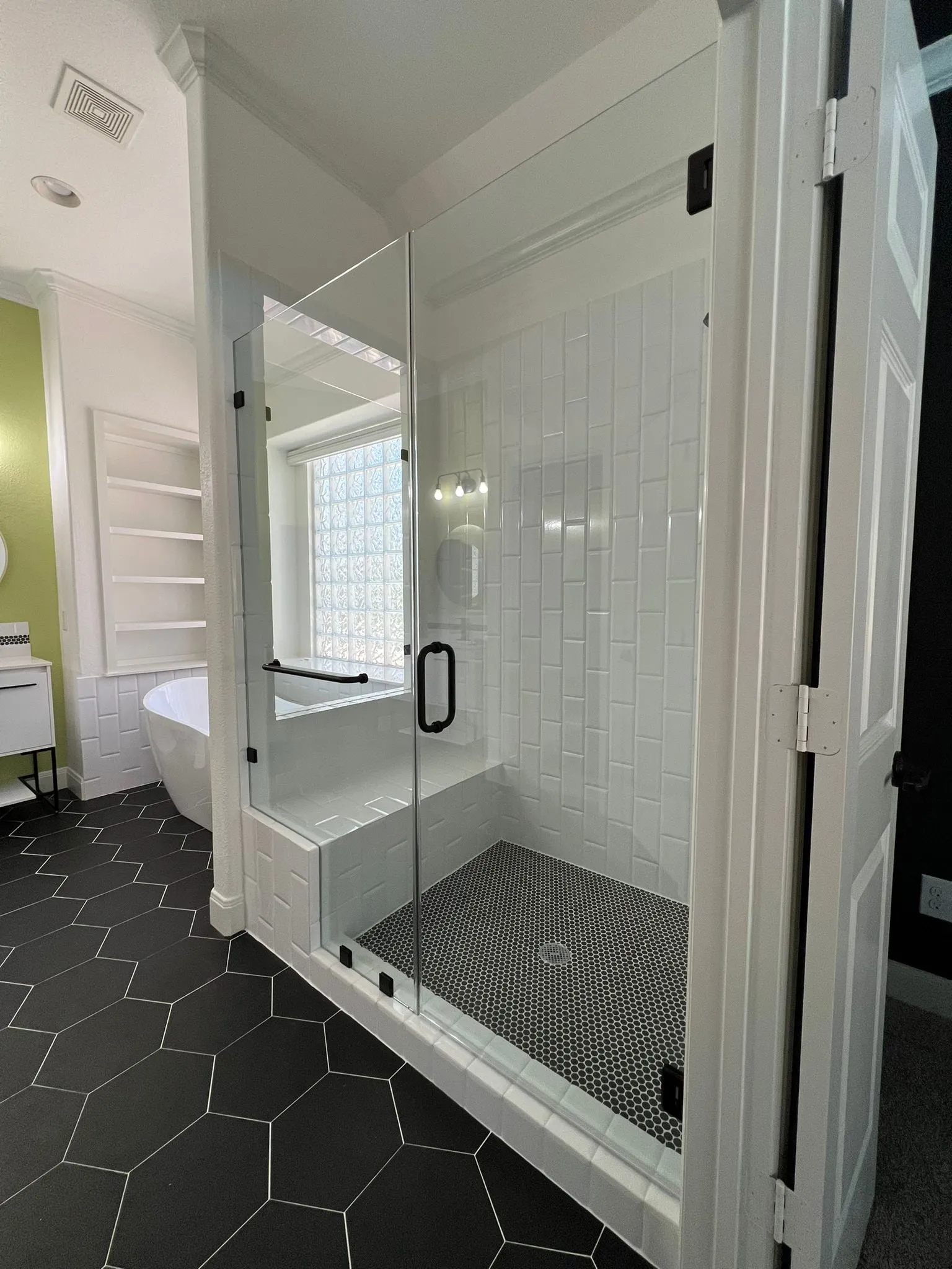Bathroom remodel with a freestanding tub, black hexagon floor tile, and a floating vanity in The Woodlands, TX