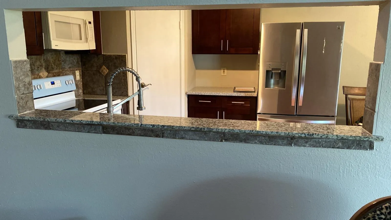 Espresso kitchen cabinetry with granite counters and a stained concrete floor in The Woodlands, TX