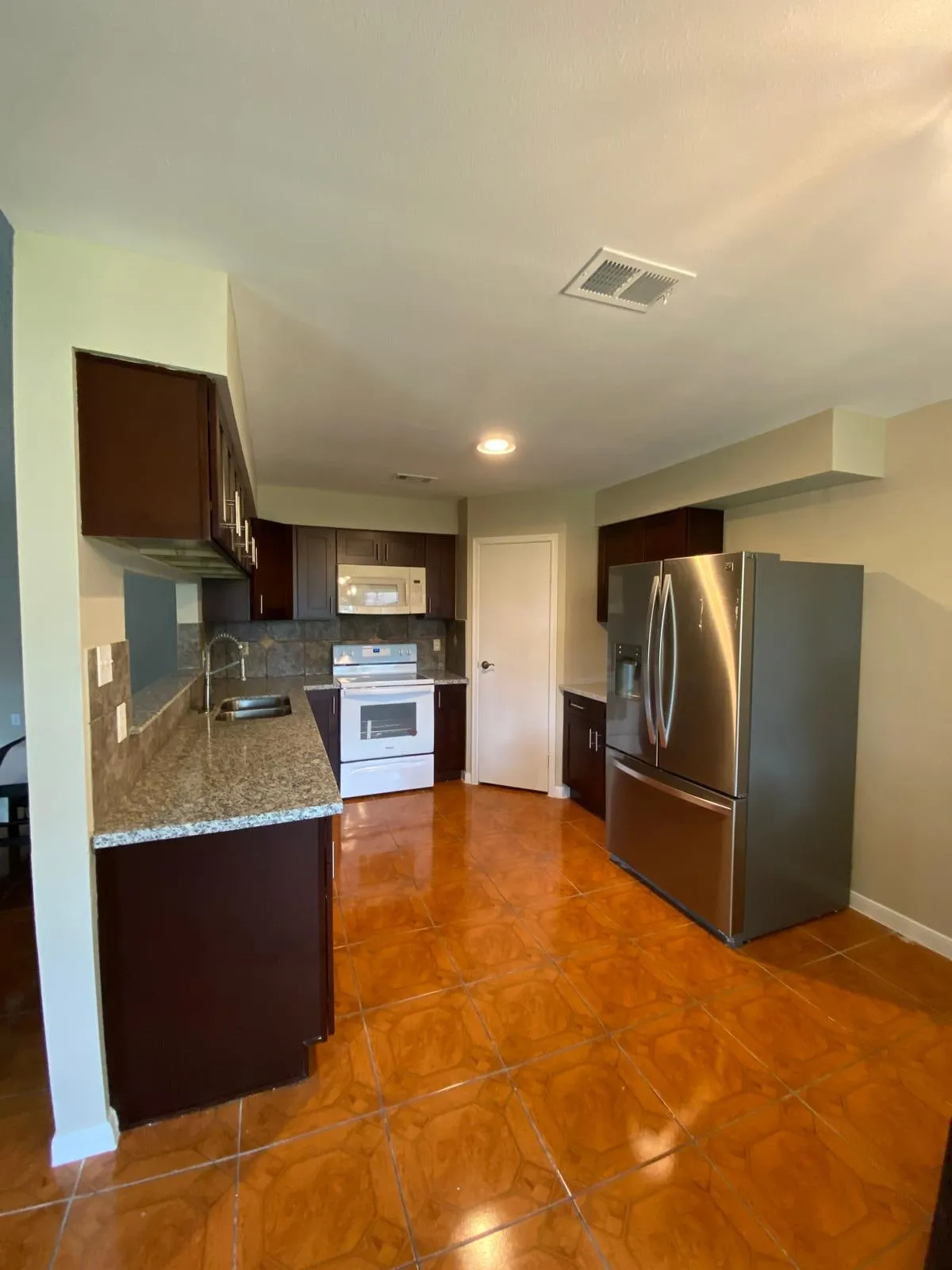 Espresso kitchen cabinetry with granite counters and a stained concrete floor in The Woodlands, TX