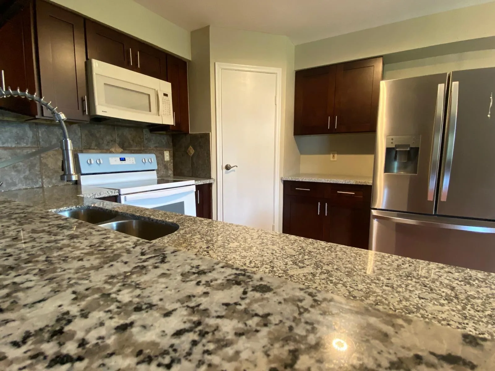 Espresso kitchen cabinetry with granite counters and a stained concrete floor in The Woodlands, TX