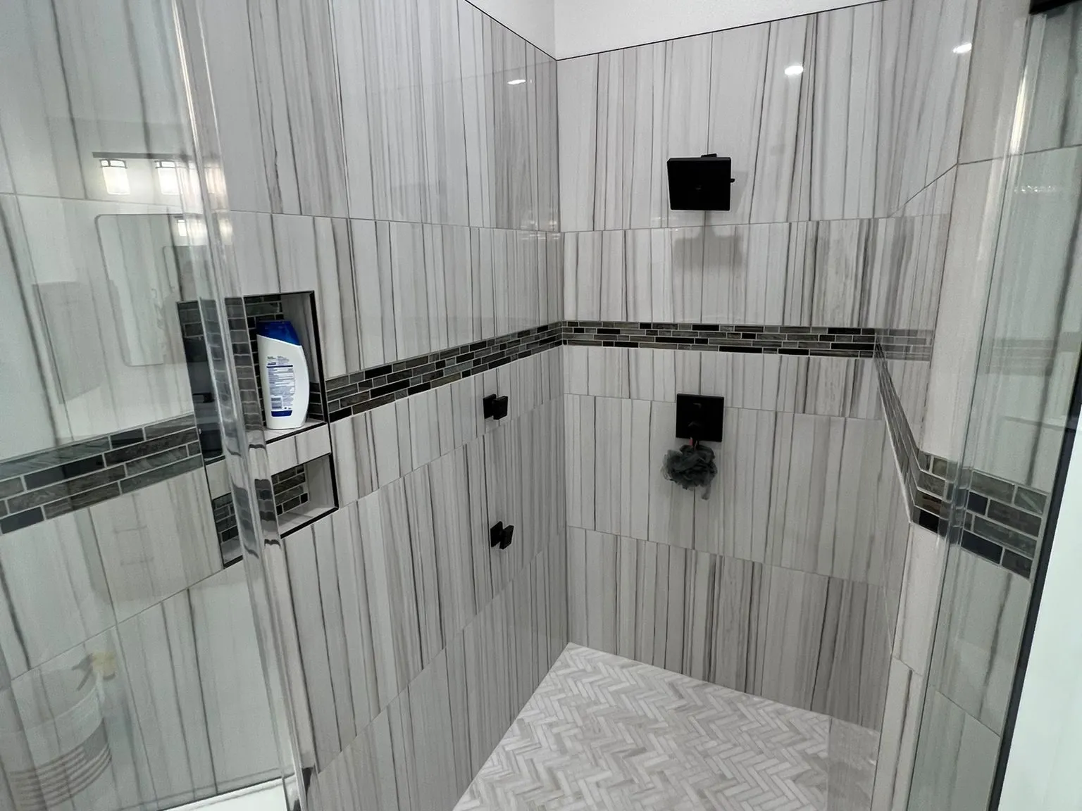 Vertically stacked stone effect tile with an accent band in a shower in The Woodlands, TX