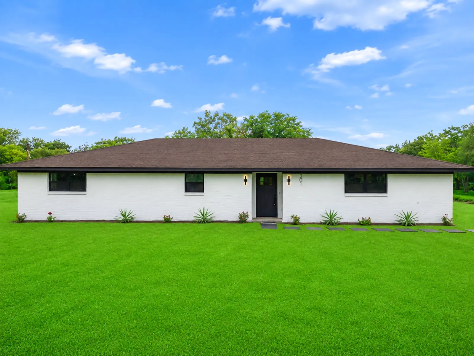 Completed whole home renovation of a single storey ranch seen from the front lawn in The Woodlands, TX